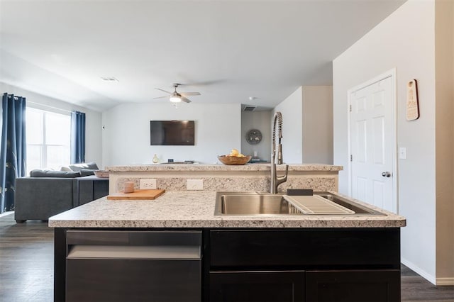 kitchen with light countertops, open floor plan, a sink, an island with sink, and dishwasher