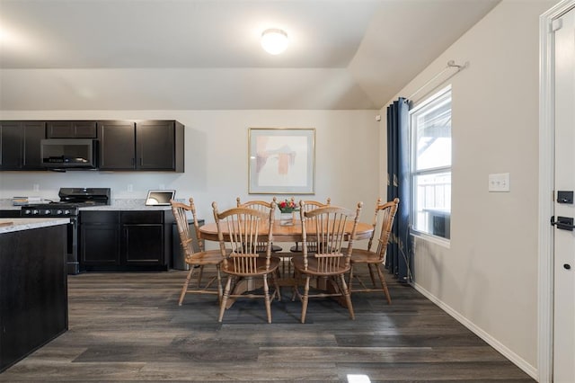 dining space featuring dark wood-style floors, vaulted ceiling, and baseboards