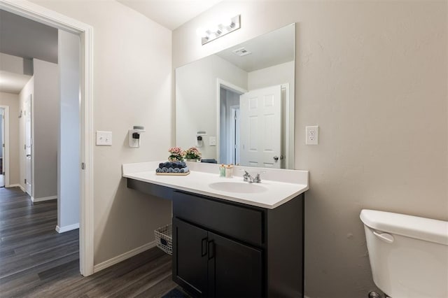 bathroom with visible vents, toilet, vanity, wood finished floors, and baseboards