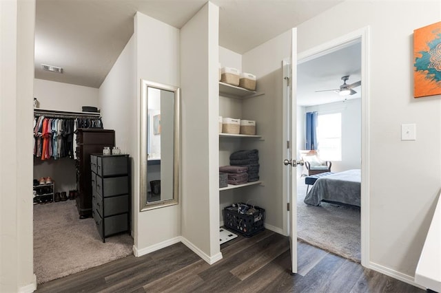 interior space featuring ceiling fan, visible vents, and dark wood-style flooring