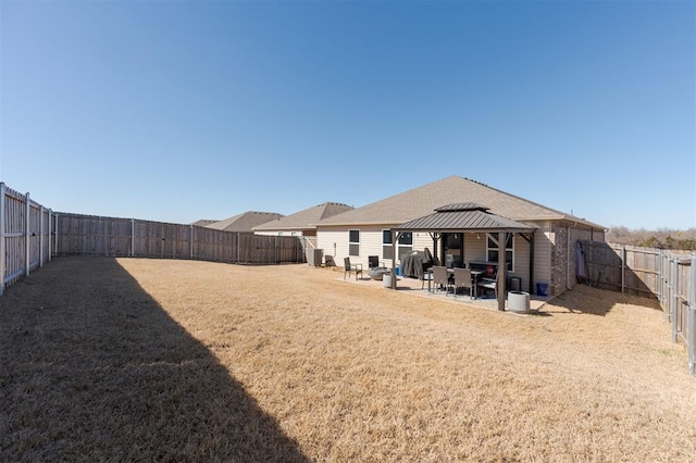 rear view of house with a patio area, a fenced backyard, a lawn, and a gazebo