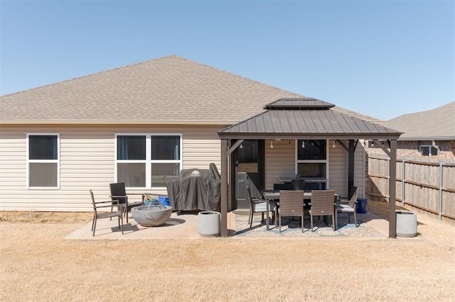 rear view of property featuring a patio area, a shingled roof, fence, and a gazebo