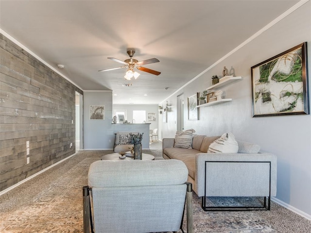 living room featuring carpet, ornamental molding, ceiling fan, wood walls, and baseboards