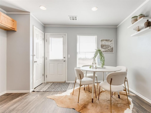 dining space with light wood-style floors, visible vents, and crown molding