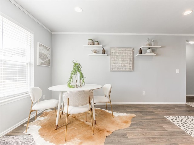 dining room with ornamental molding, wood finished floors, and baseboards