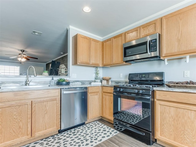 kitchen featuring visible vents, appliances with stainless steel finishes, light brown cabinets, a sink, and light wood-type flooring