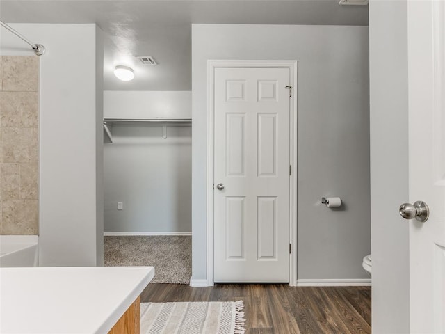 bathroom with toilet, baseboards, visible vents, and wood finished floors