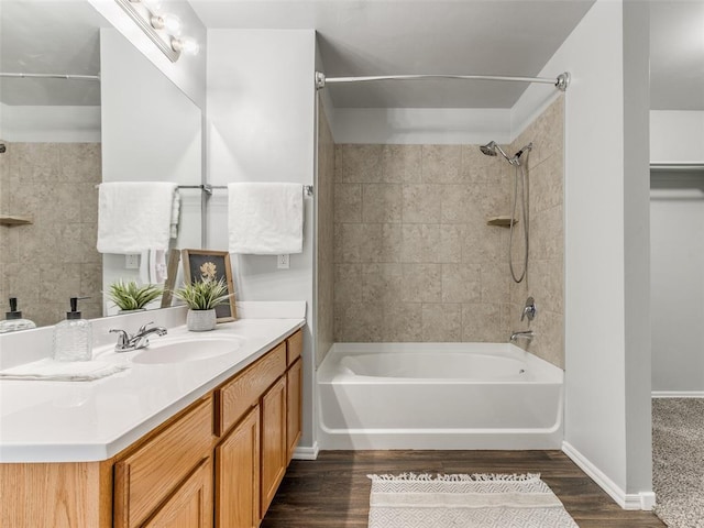 bathroom featuring vanity, baseboards, wood finished floors, and bathing tub / shower combination