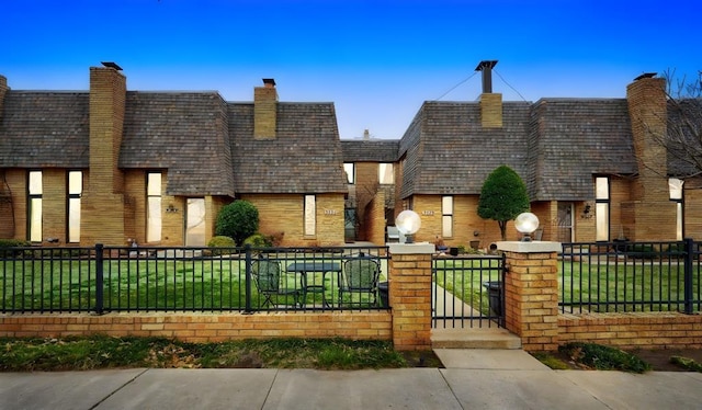 view of front of house featuring a fenced front yard, brick siding, and a front lawn