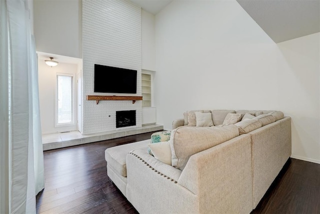 living area featuring high vaulted ceiling, dark wood-style flooring, a fireplace, and baseboards