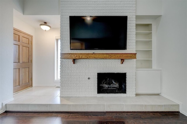 interior details with baseboards, a fireplace, built in features, and wood finished floors