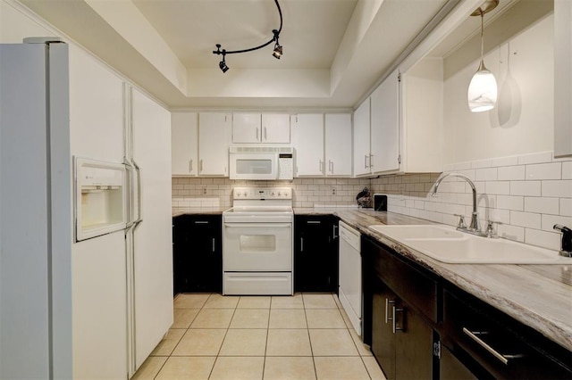 kitchen with white appliances, a sink, a tray ceiling, light countertops, and backsplash