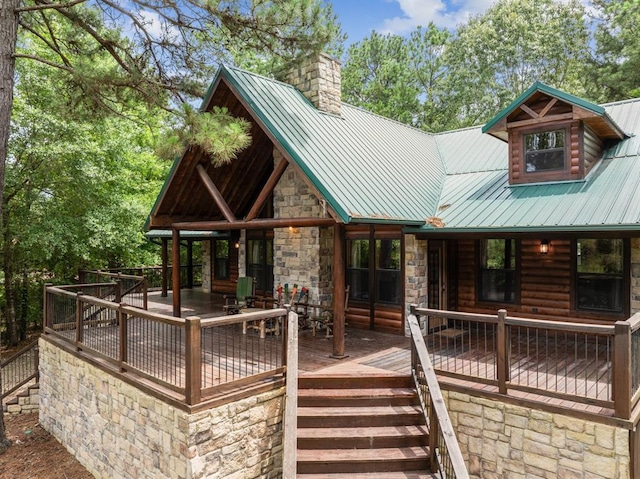 view of front of home featuring stone siding, a chimney, metal roof, and a wooden deck