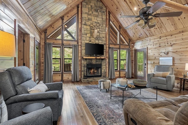 living room featuring wooden ceiling, wood-type flooring, wood walls, and a stone fireplace