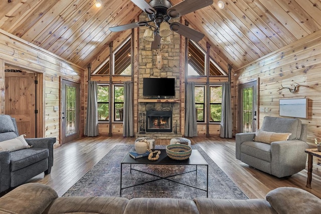 living room with a fireplace, wood-type flooring, wood walls, high vaulted ceiling, and wooden ceiling