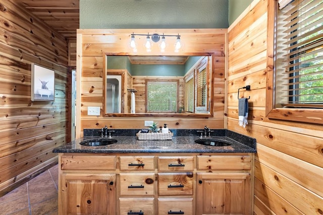 bathroom featuring wood walls, a sink, and tile patterned floors