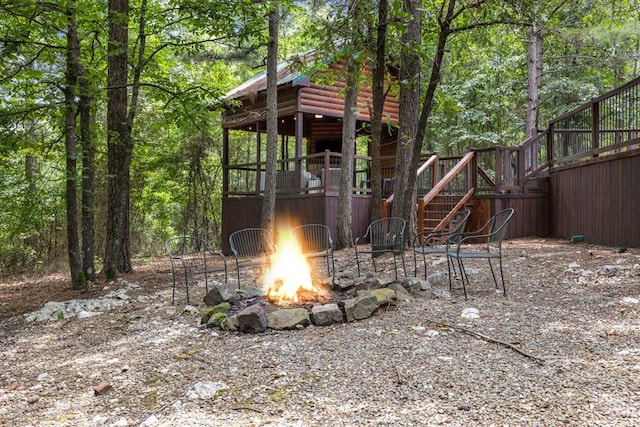 view of jungle gym featuring a forest view, an outdoor fire pit, and a wooden deck