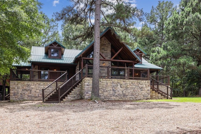 rear view of property with covered porch, stairs, and metal roof