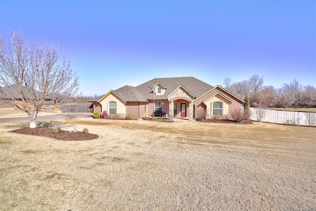 view of front of house with stone siding and fence