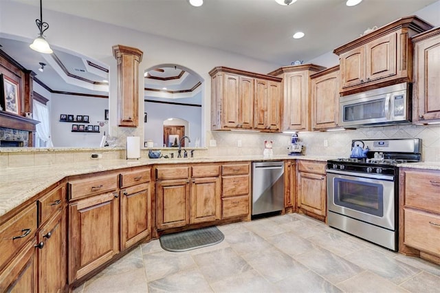 kitchen with decorative backsplash, appliances with stainless steel finishes, a raised ceiling, and crown molding