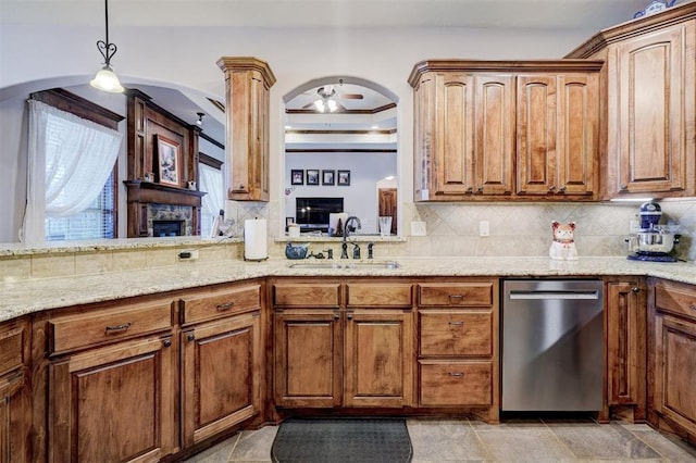 kitchen featuring arched walkways, a sink, stainless steel dishwasher, light stone countertops, and tasteful backsplash