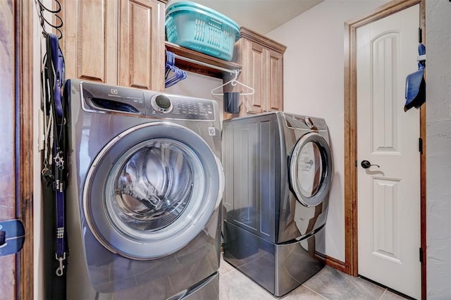 laundry area with washer and dryer, cabinet space, and light tile patterned floors