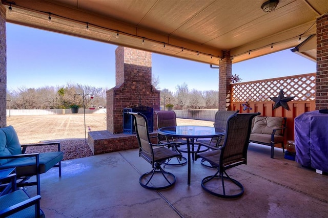 view of patio / terrace with area for grilling, an outdoor brick fireplace, outdoor dining space, and a fenced backyard