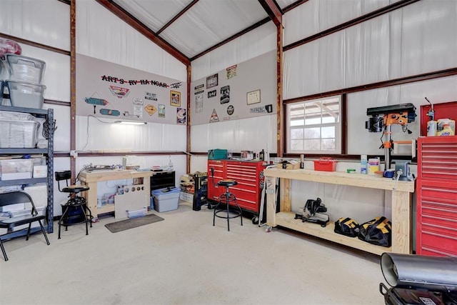 miscellaneous room featuring concrete floors, a workshop area, and high vaulted ceiling