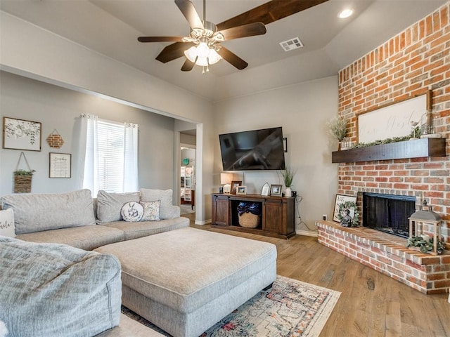 living room with a fireplace, wood finished floors, a ceiling fan, visible vents, and baseboards