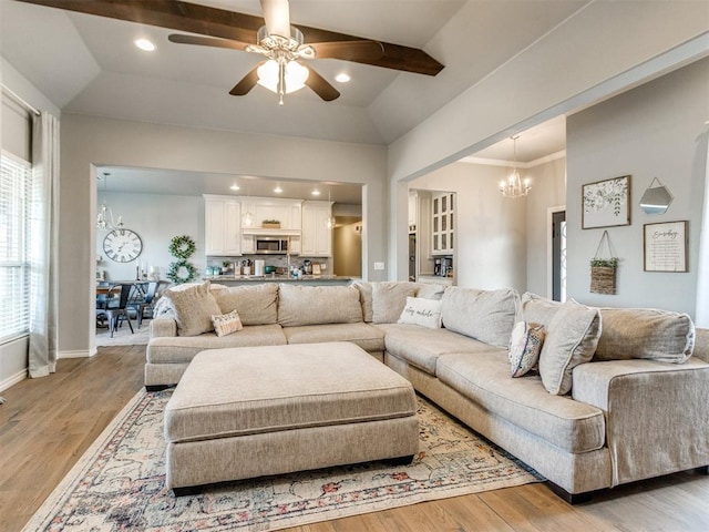 living room with light wood finished floors, baseboards, ornamental molding, ceiling fan with notable chandelier, and recessed lighting