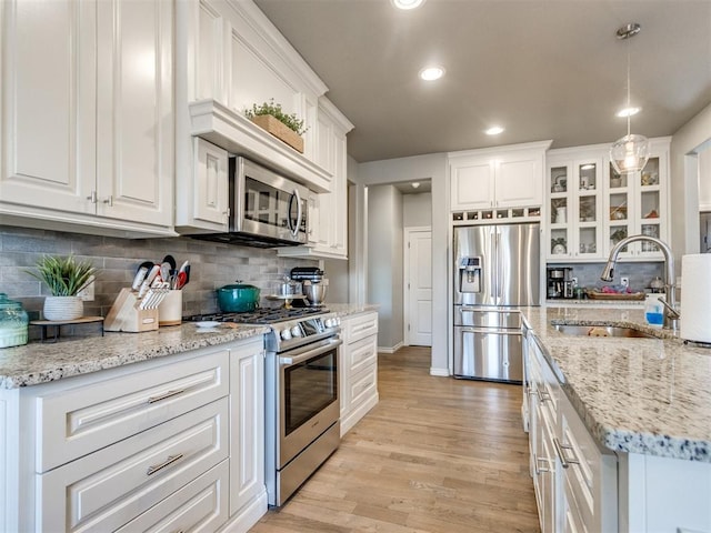 kitchen featuring appliances with stainless steel finishes, a sink, light wood-style floors, and white cabinets