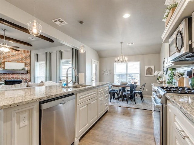 kitchen featuring stainless steel appliances, a sink, visible vents, a brick fireplace, and light wood finished floors