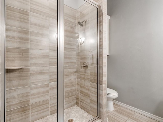 bathroom with a stall shower, tile patterned floors, toilet, and baseboards