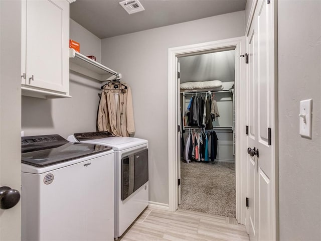 clothes washing area featuring visible vents, cabinet space, washer and clothes dryer, and baseboards