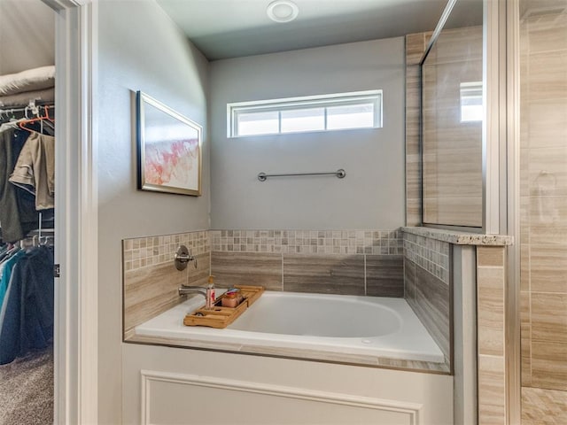 bathroom with a walk in closet and a bath