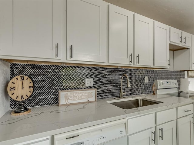 kitchen featuring white appliances, white cabinets, a sink, and light stone countertops