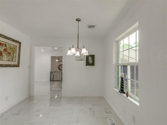 empty room featuring marble finish floor, visible vents, baseboards, and an inviting chandelier