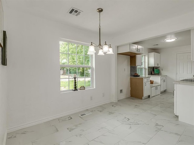 unfurnished dining area featuring marble finish floor, visible vents, and baseboards