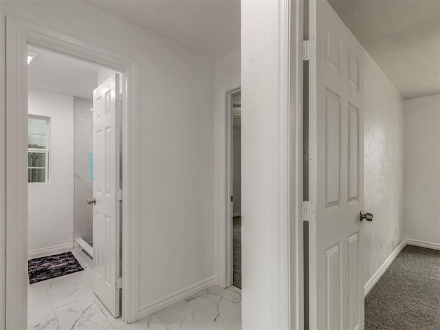 hallway featuring marble finish floor and baseboards