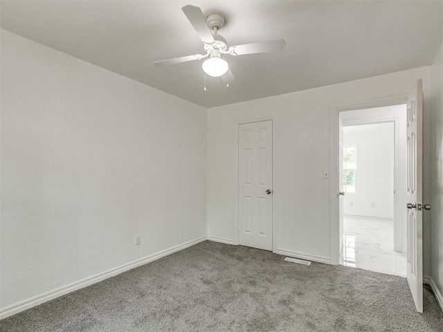 unfurnished bedroom featuring carpet flooring, ceiling fan, visible vents, and baseboards