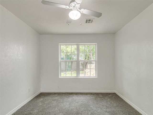 empty room with carpet floors, visible vents, and baseboards