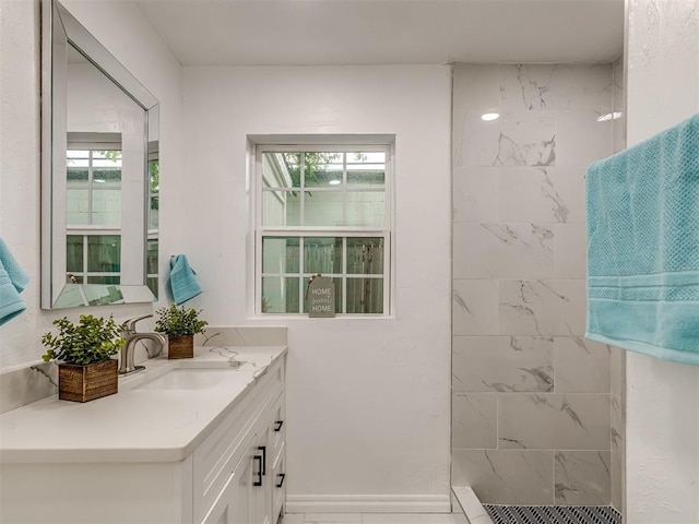 bathroom featuring baseboards, tiled shower, and vanity