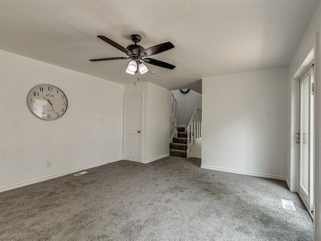 unfurnished living room featuring stairs, carpet floors, ceiling fan, and baseboards