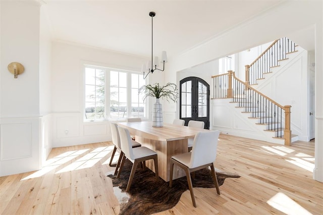 dining room with stairs, french doors, crown molding, and a decorative wall