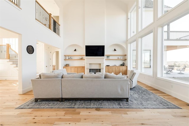 living area with stairway, a fireplace, wood finished floors, and baseboards