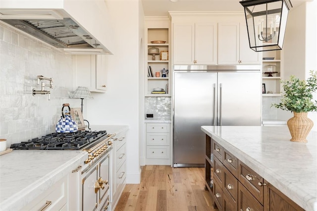 kitchen featuring light wood finished floors, open shelves, white cabinetry, ventilation hood, and built in refrigerator