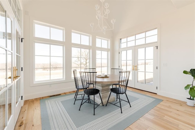 interior space featuring light wood-style flooring, a high ceiling, visible vents, and french doors