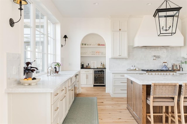 kitchen featuring white cabinets, light wood-style flooring, custom range hood, wine cooler, and open shelves