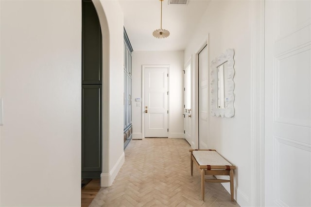 corridor featuring arched walkways, visible vents, and baseboards