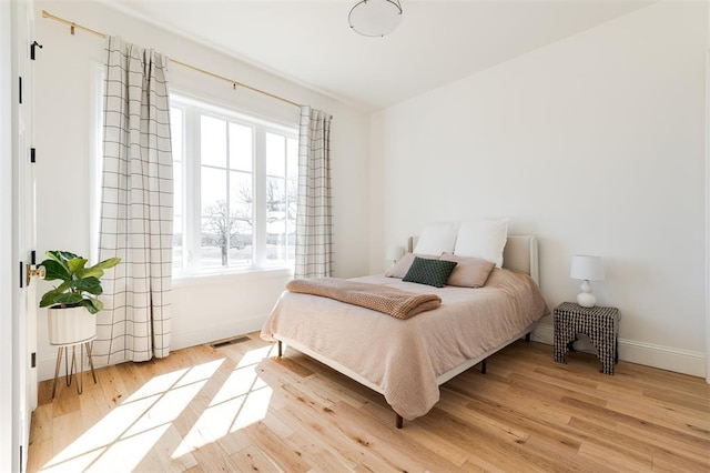 bedroom featuring light wood-style flooring, visible vents, and baseboards